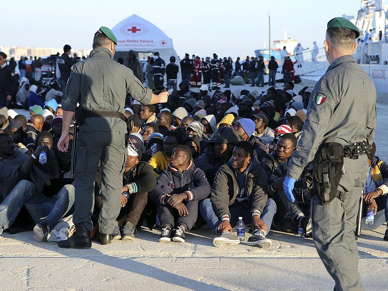 Migrants rest after they disembarked in the Sicilian harbour of Augusta