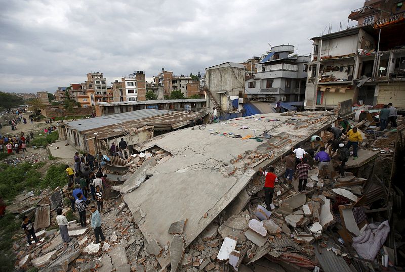 Varias personas observan una casa derruida en Katmandú, Nepal