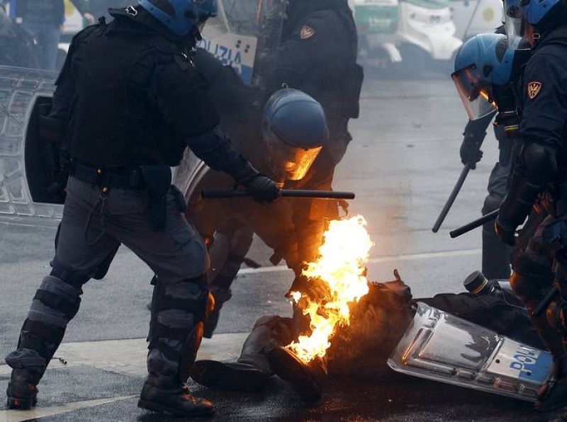 Agentes de la Policía ayudan a un compañero en llamas que ha sufrido el impacto de un cóctel molotov.