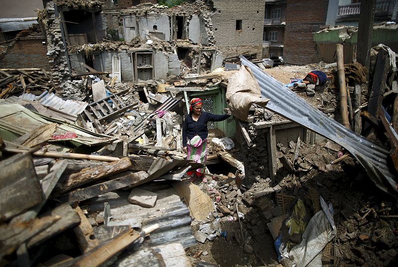 A woman stands on the debris of collapsed houses after a fresh 7.3-magnitude earthquake struck Nepal, in Sankhu