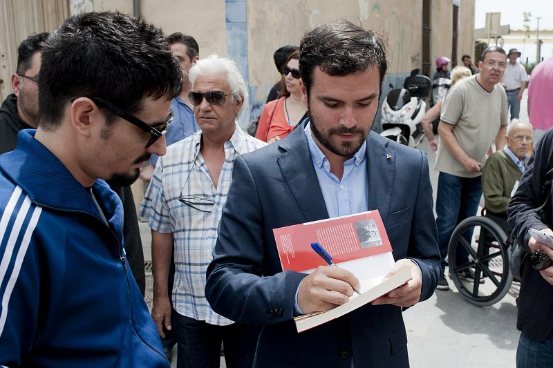 El candidato de IU a la Moncloa, Alberto Garzón (d), firma un autógrafo a un simpatizante en Blanes, Girona