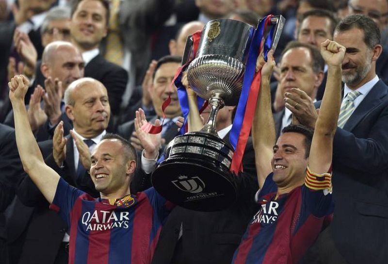 Los capitanes del FC Barcelona Xavi Hernandez (D) y Andrés Iniesta (I) levantan el trofeo.