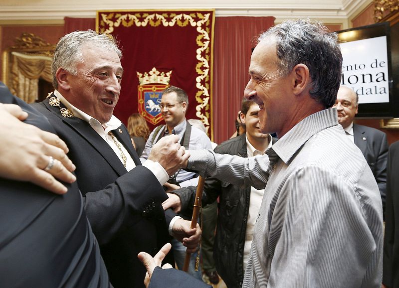 Joseba Asiron, de EH Bildu, recibe la felicitación del candidato a la Presidencia del Gobierno de Navarra, Adolfo Araiz, también de EH Bildu, tras el acto celebrado en el salón de plenos donde el primero ha sido elegido alcalde de Pamplona