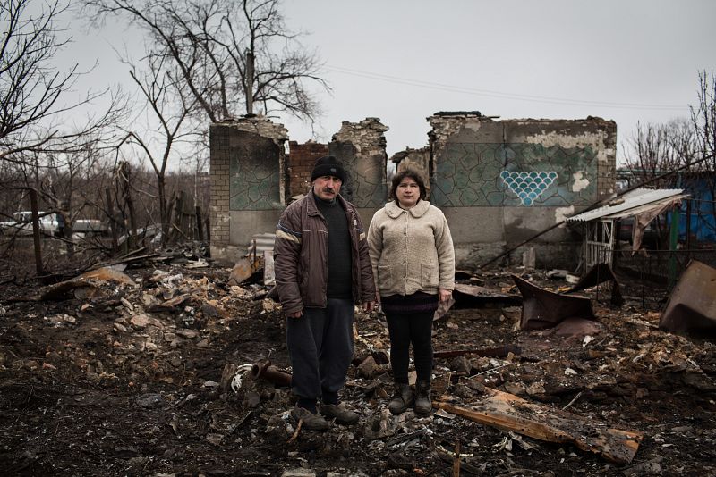 Yurvi y Tatiana posan entre las ruinas del que era su hogar en Nikishino, en el este de Ucrania.