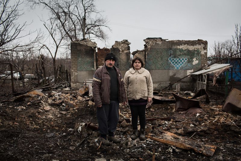 Yurvi y Tatiana posan entre las ruinas del que era su hogar en Nikishino, en el este de Ucrania.