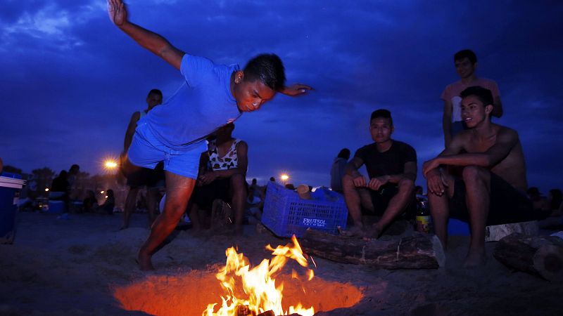 Un joven salta por encima de una hoguera en la playa de la Malvarrosa, en Valencia.