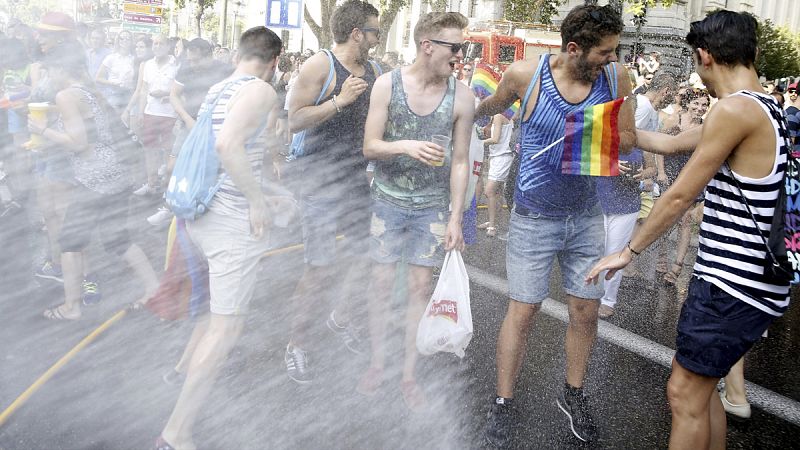 Un grupo de manifestantes en la marcha del Orgullo Gay recibe un manguerazo de los bomberos contra el calor de Madrid.