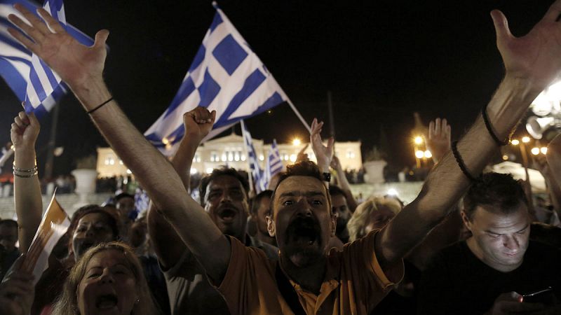 Un partidario del 'no' alza los brazos en señal de victoria rodado de banderas de Grecia en la plaza Syntagma de Atenas.