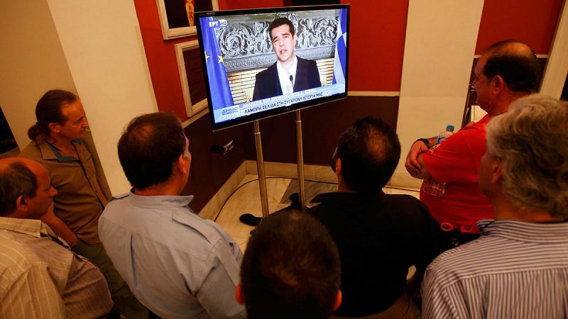 Un grupo de hombres sigue atentamente el discurso televisado del primer ministro griego, Alexis Tsipras, tras conocerse el resultado de refréndum.
