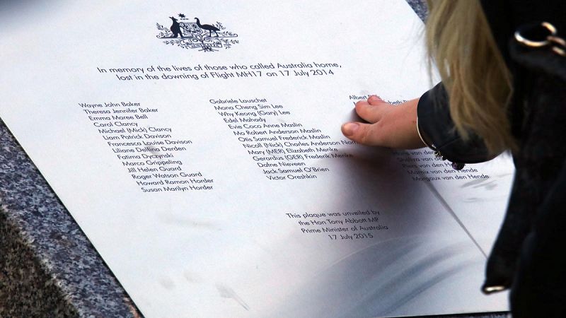 Un familiar de una de las víctimas del vuelo MH17 toca la placa conmemorativa en el exterior del Parlamento de Canberra (Australia)