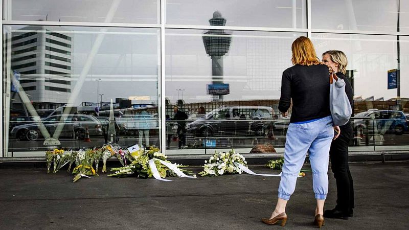 Dos mujeres se detienen ante los ramos de flores colocados en la terminal de salida del aeropuerto de Schipol (Ámsterdam) en recuerdo de las víctimas del vuelo MH17