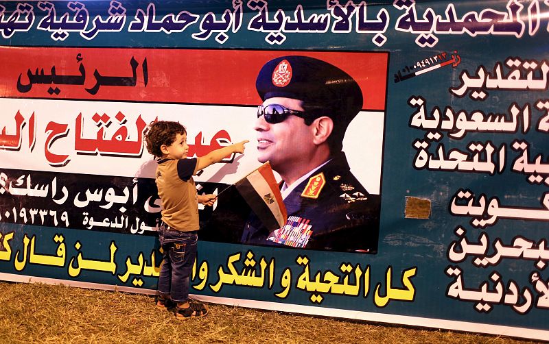 A child points to a picture of President Abdel Fattah al-Sisi as he poses for picture while people gather to celebrate in Tahrir square in Cairo