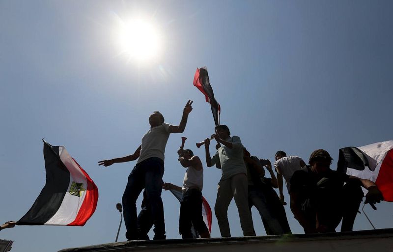 People cheer while carrying national flags in as they gather in Tahrir square to celebrate an extension of the Suez Canal 