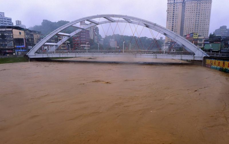 Un hombre camina por un puente sobre el río Jingmei, desbordado a su paso por Taipei, después de que el tifón Soudelor golpeara Taiwán.