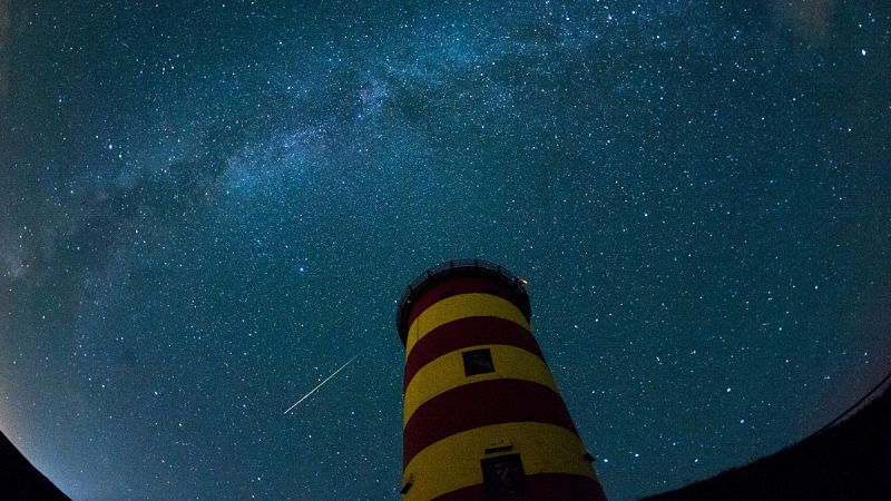 Una estrella fugaz cruza el cielo nocturno detrás del faro de Pilsum, noroeste de Alemania