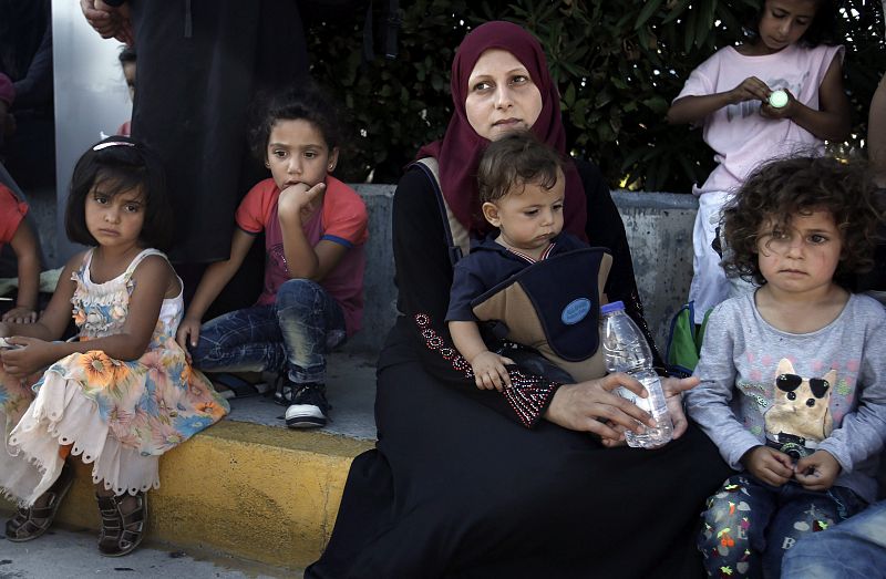 Un grupo de refugiados sirios espera el autobús en el puerto ateniense de Pireo