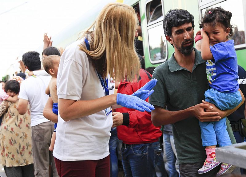 A medic speaks to a migrant holding his daughter at the railway station in the town of Bicske