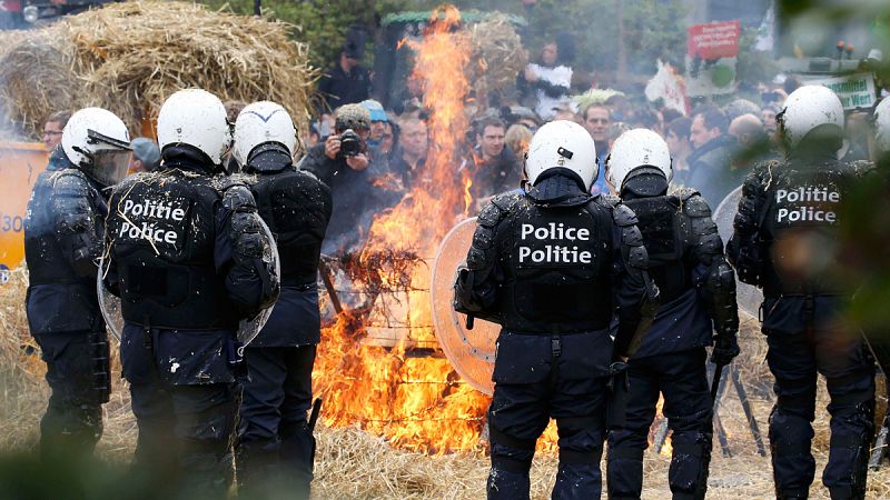 Unos ganaderos incendian en Bruselas un montón de heno ante los antidisturbios.