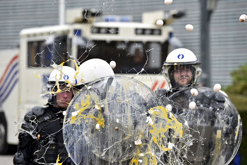 Varios agentes antidisturbios reciben impactos de huevos en sus escudos mientras protegen las instituciones comunitarias en Bruselas