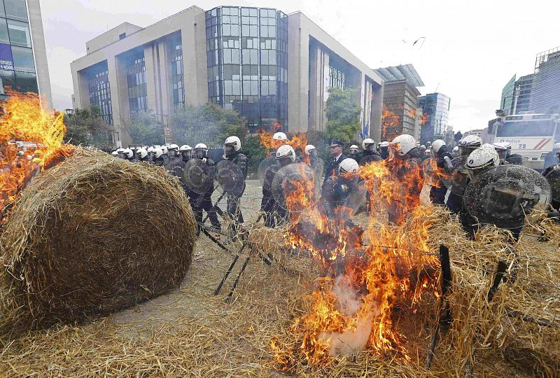 Los policías antidisturbios belgas defienden las instituciones europeas mientras los ganaderos que protestan por el precio de la leche queman un montón de heno