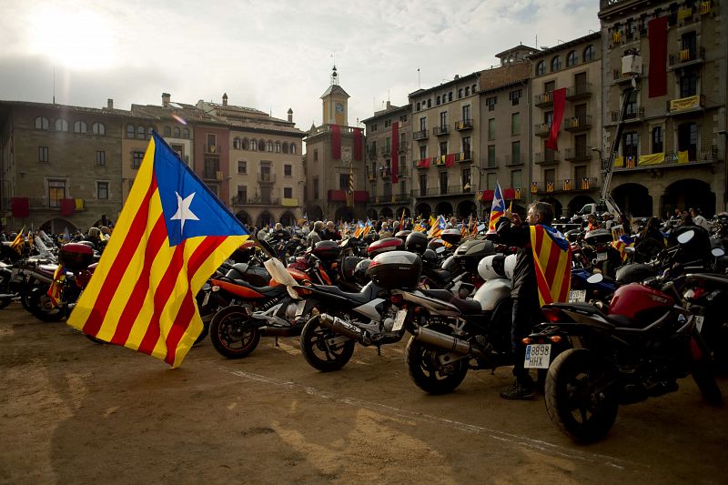 Un hombre retrata una bandera estelada colgada en una moto.