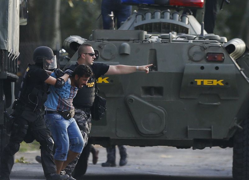 Hungarian riot policemen take hold of a migrant in Roszke