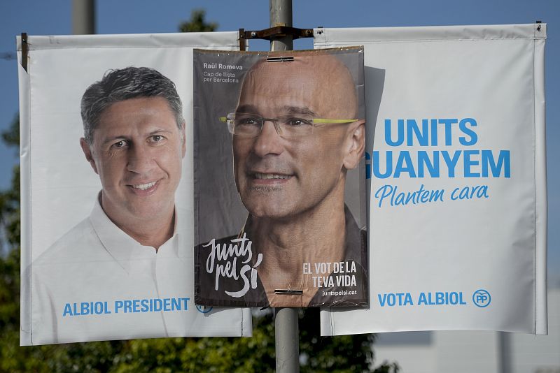 Dos posters electorales de los candidatos del PP y de Junts pel Sí en las elecciones catalanas, en una misma farola, en Barcelona.