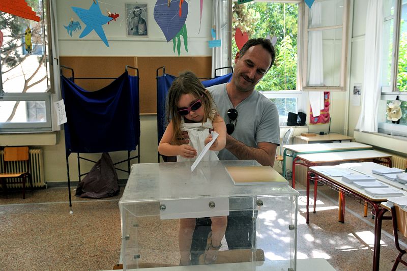Una niña introduce el sobre con el voto de su padre en la urna