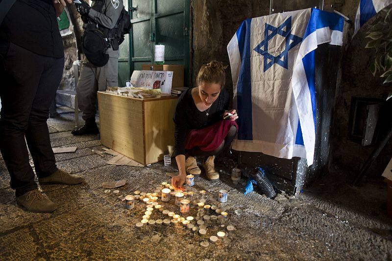 Una mujer israelí enciende una vela en el lugar donde una familia judía fue víctima de un ataque el pasado 3 de octubre en Jerusalén