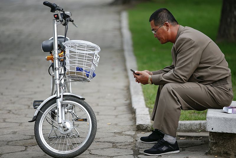 Un hombre junto a una bicicleta eléctrica utiliza un teléfono móvil en el centro de Pyongyang. Signos de modernidad en la capital de Corea del Norte cuando prepara el 70 aniversario del Partido de los Trabajadores