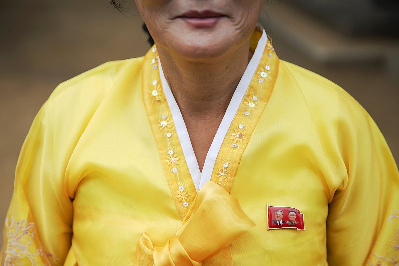 Una mujer ataviada con ropas tradicionales luce un pin con las efigies de Kim Il Sung y Kim Jong Il, un complemento es obligatorio para los norcoreanos