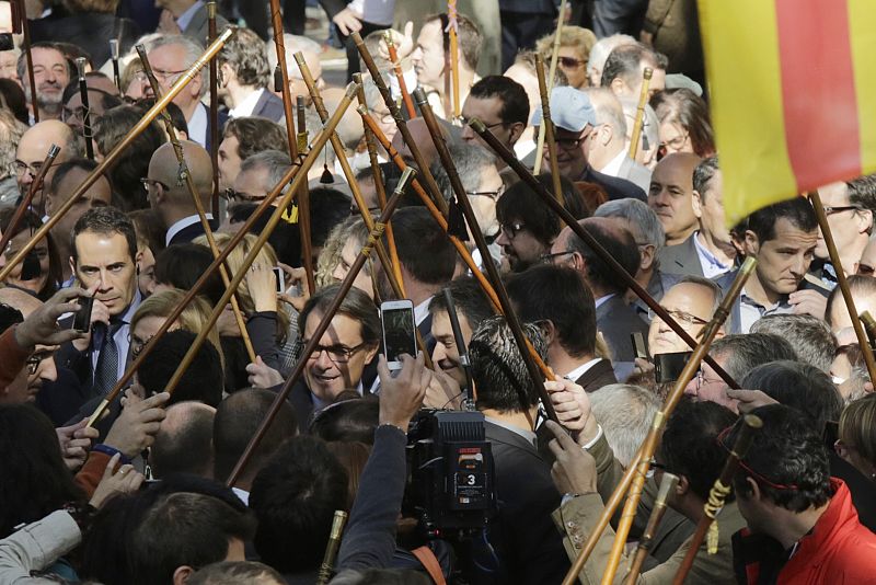 El presidente catalán, Artur Mas, pasa por debajo de los bastones de mando de los alcaldes que le acompañaron ante la sede del TSJC, después de terminar su declaración, de algo más de una hora,