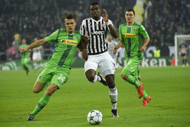 Paul Pogba lucha una bola con Granit Xhaka.