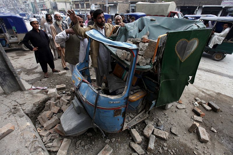 Un hombre retira los escombros caídos sobre su 'rickshaw' tras el seísmo en Peshawar