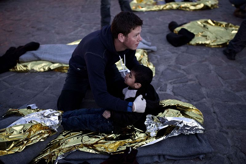 Uno de los voluntarios que atendieron a los refugiados sostiene a un chico en Lesbos