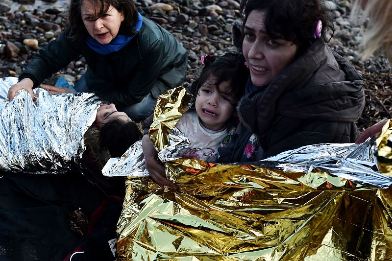 Una mujer con una niña en brazos llora al alcanzar la costa de la isla de Lesbos