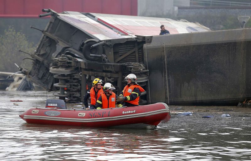 Los equipos de rescate buscan los restos del tren desde una pequeña embarcación en el canal donde cayó la máquina