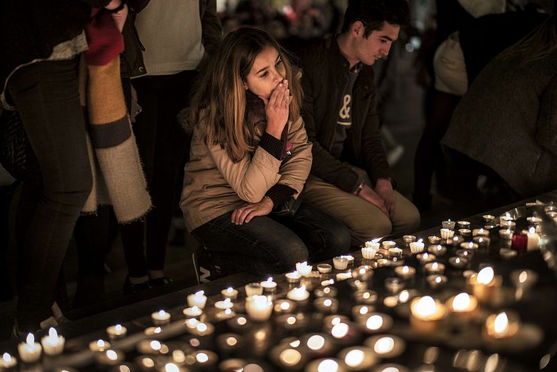 Una joven se une al minuto de silencio en frente de un homenaje a las víctimas de París en Lyon