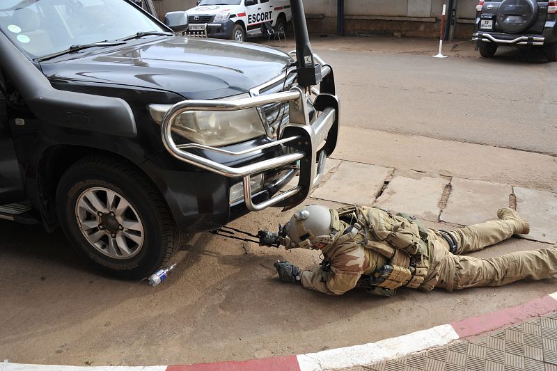 Un miembro de las fuerzas especiales revisa un coche aparcado en las proximidades del hotel Radisson Blu, después del asalto de las fuerzas de seguridad