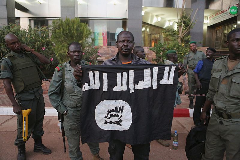 Oficiales de seguridad de Mali muestran una bandera portada por los terroristas