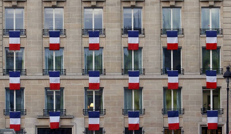Banderas francesas ondean en las ventanas en un edificio cerca de Los Inválidos