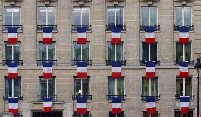 Banderas francesas ondean en las ventanas en un edificio cerca de Los Inválidos
