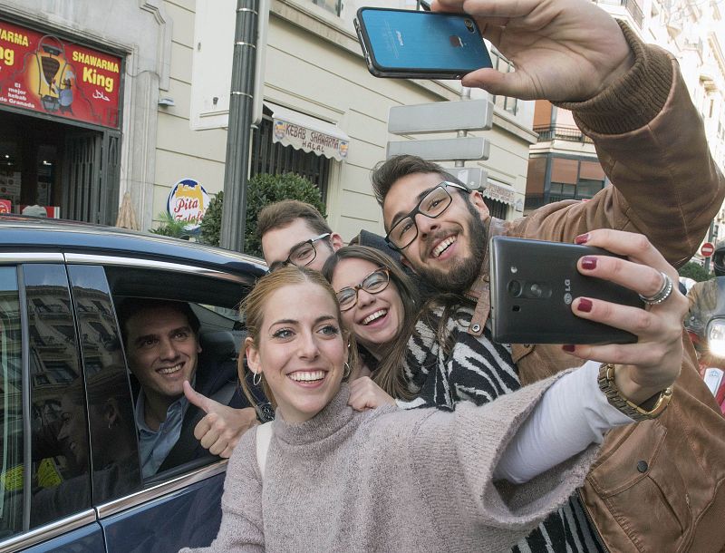 El presidente de Ciudadanos y candidato a la presidencia del Gobierno, Albert Rivera, dentro del coche se deja hacer un selfie con un grupo de jóvenes, en Granada.
