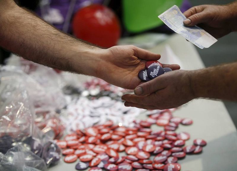 Un simpatizante de Podemos compra chapas en un mitin de la formación en Barcelona. 