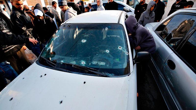 Un grupo de palestinos observan el coche tiroteado de uno de los supuestos atacantes palestinos abatido por soldados israelíes en Qalandia, Cisjordania, el 16 de diciembre de 2015.