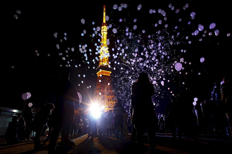 People release balloons at the turn of the New Year at a hotel in front of the landmark Tokyo Tower in Tokyo