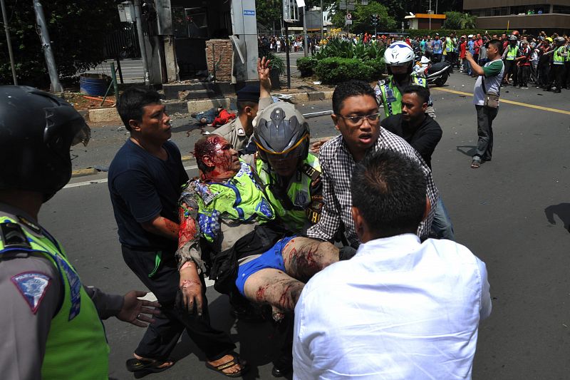Policías indonesios trasladan a un agente herido en el atentado frente a un centro comercial en Yakarta.