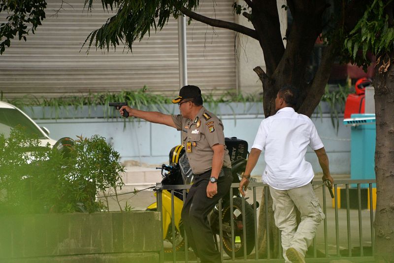 Un policía indonesio dispara durante el tiroteo que se ha desatado después de las explosiones