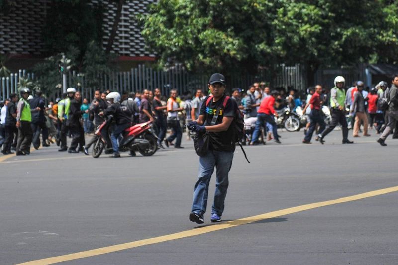 Un hombre, identificado posteriormente por la prensa local como uno de los asaltantes de Yakarta, empuña una pistola mientras la gente huye a su espalda