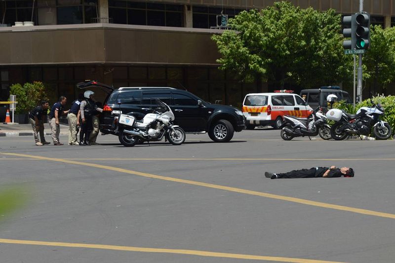 La policía toma posiciones ante el café, mientras uno de los cadáveres permanece tendido en medio de la avenida